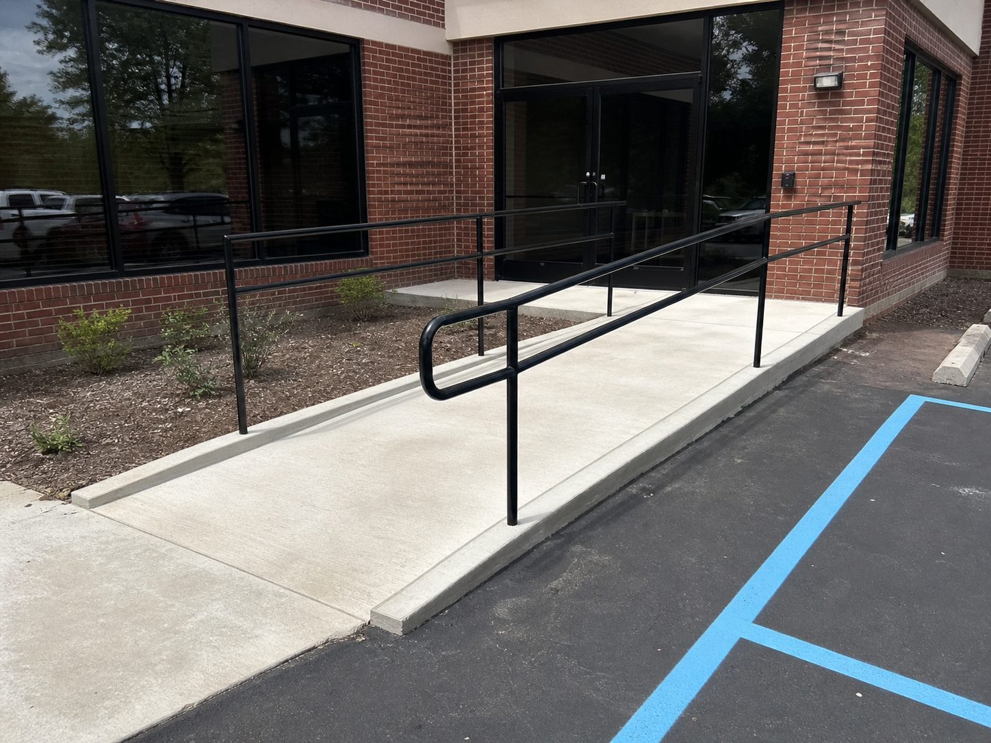 Finished commercial ADA concrete ramp with handrails and accessible route at a Lee's Summit, MO building